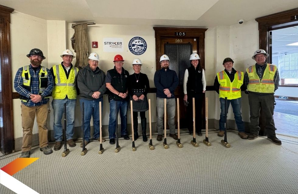 The Stryker team at a job site holding golden sledge hammers